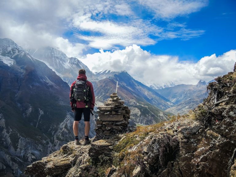 man standing on top of mountain beside cairn stones